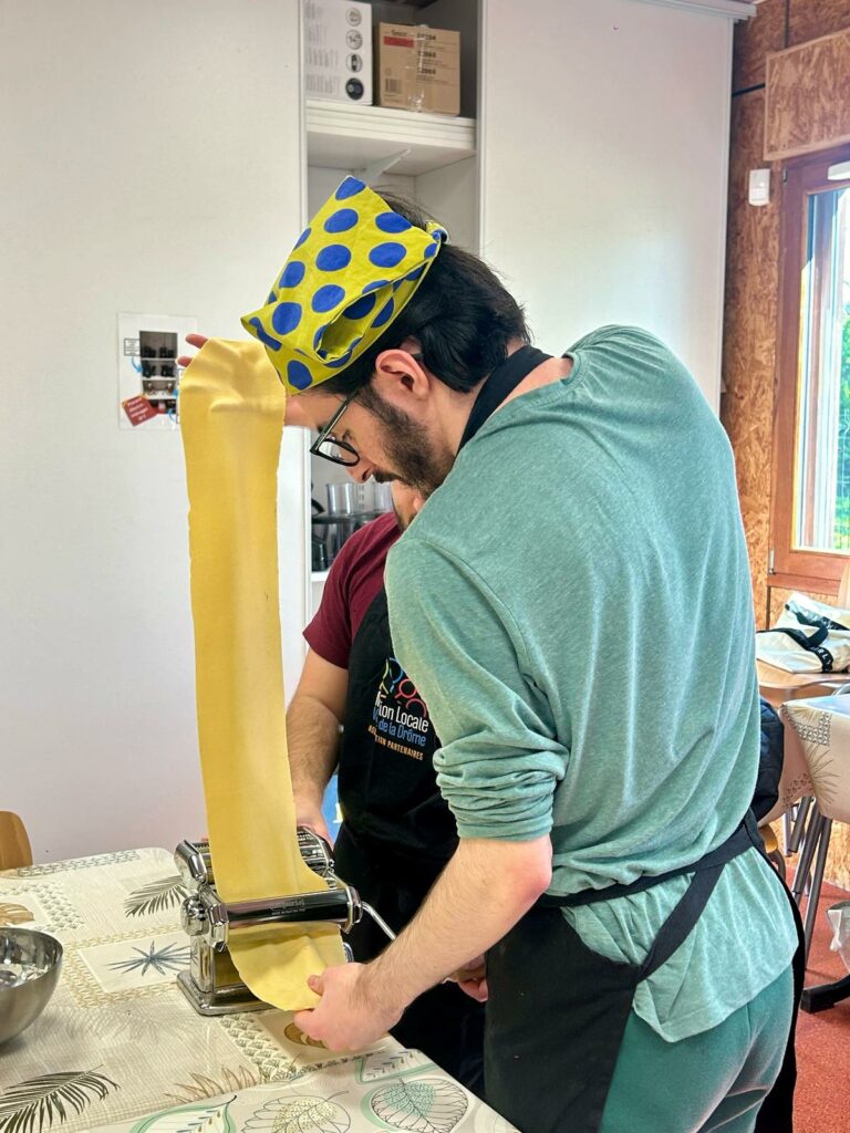 Photo d'un participant lors d'un atelier de cuisine sensorielle, en train de laminer une pate fraiche maison.